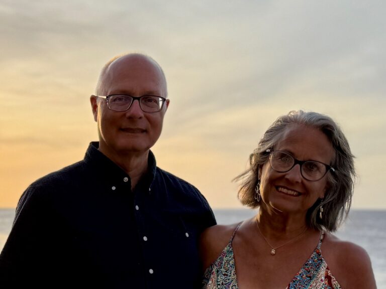 A man and woman at sunset on the Caribbean Sea. They are the authors of the website Retirement Unscripted,