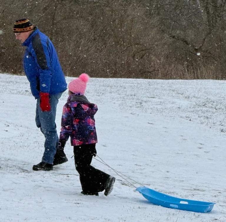 A man playing with a small child on a snowy day in Illinois
