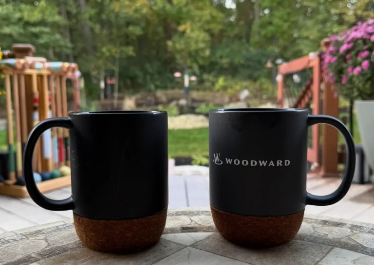 Two coffee cups on a table on a deck. Used as the feature image in When the Alarm clock stops: do we drift or design?