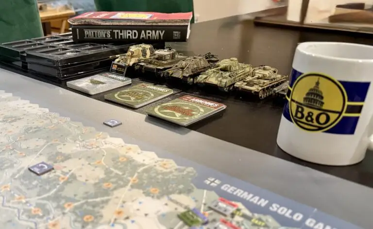 Patton's Third Army book, WWII tank models, Ardennes game map, and a B&O Railroad coffee mug on a game table