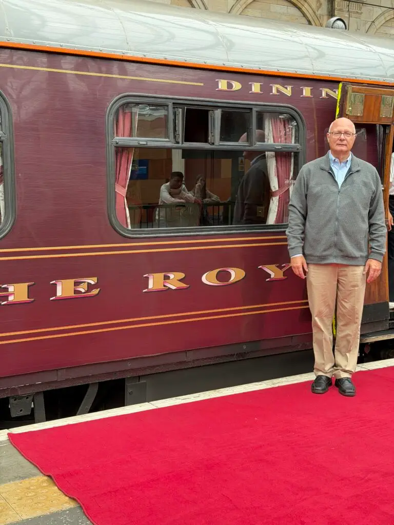 A man next to the Royal Scotsman train