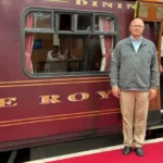 A man next to the Royal Scotsman train